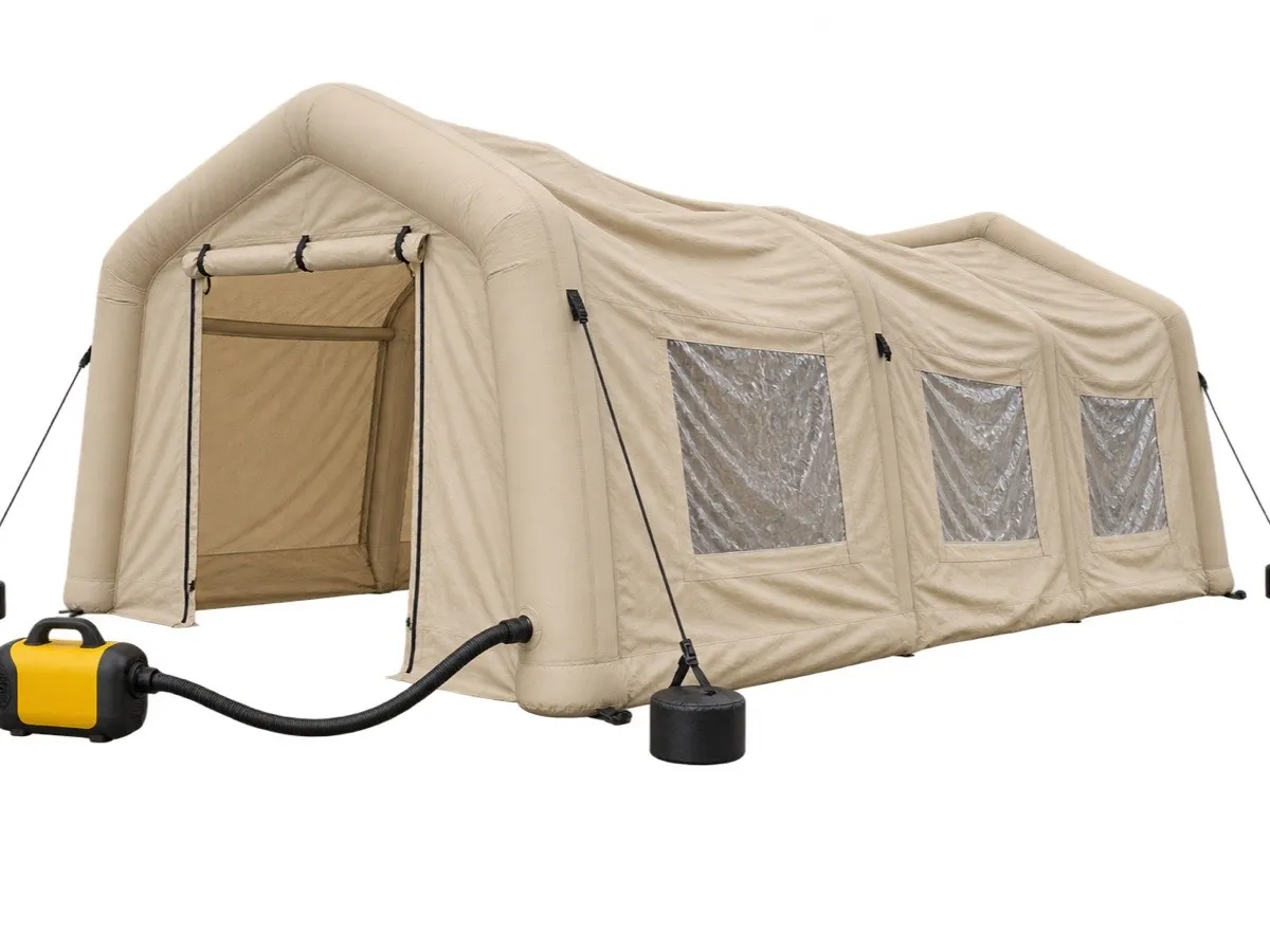 Illustration: a tan inflatable tent part-way through inflation on the ground, connected by hose to a yellow air blower